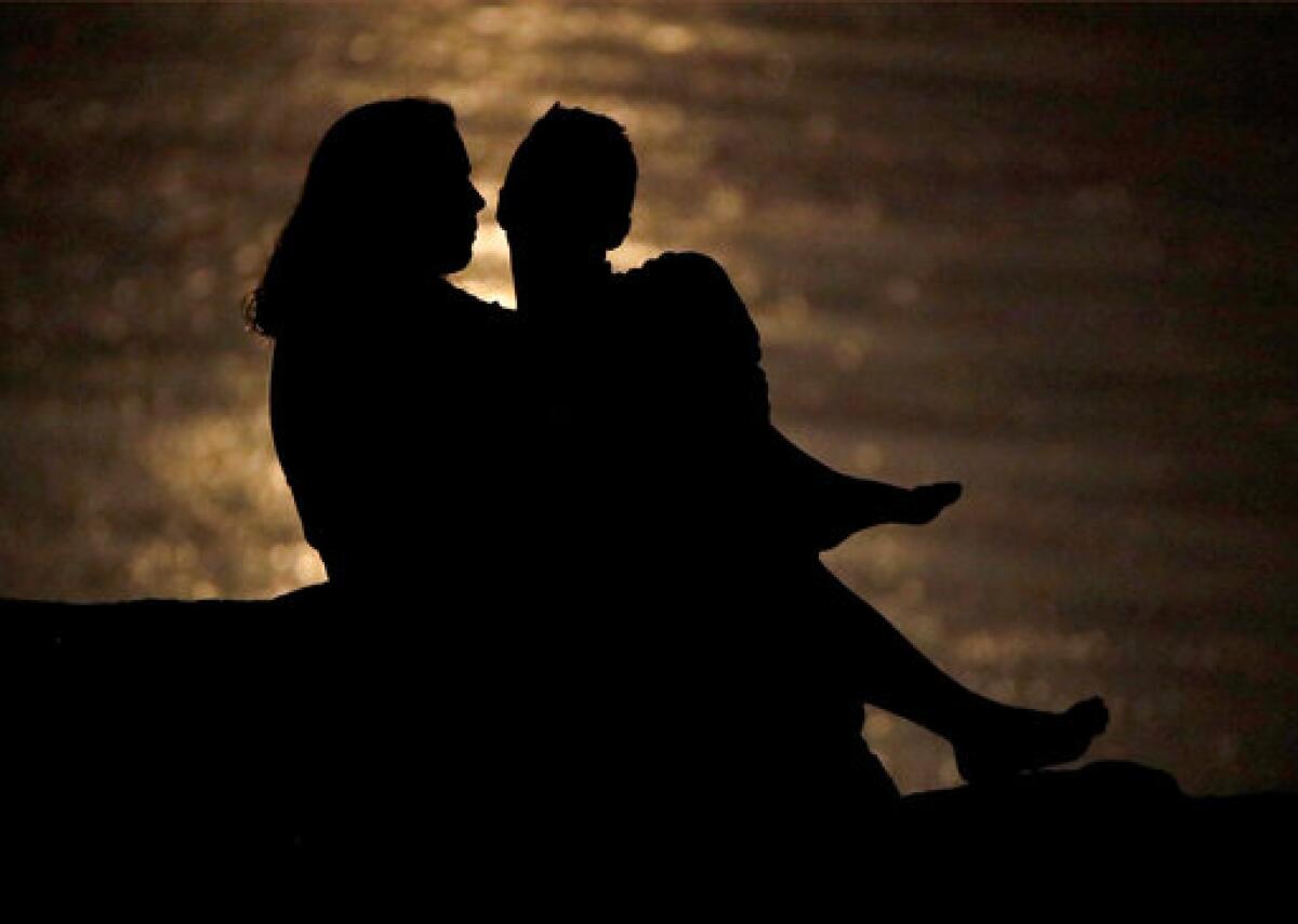 Silueta de una pareja que conversa bajo la luz de la luna en la ribera del río Missouri en Kansas City el 27 de junio del 2018. Ambientes como este pueden ser propicios para hablar de las finanzas de una pareja, charlas que son vitales para la salud de la relación, según expertos. (AP Photo/Charlie Riedel, File)