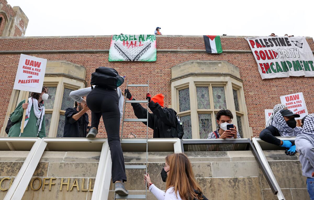 UCLA protesters climb a ladder at Kerckhoff Hall