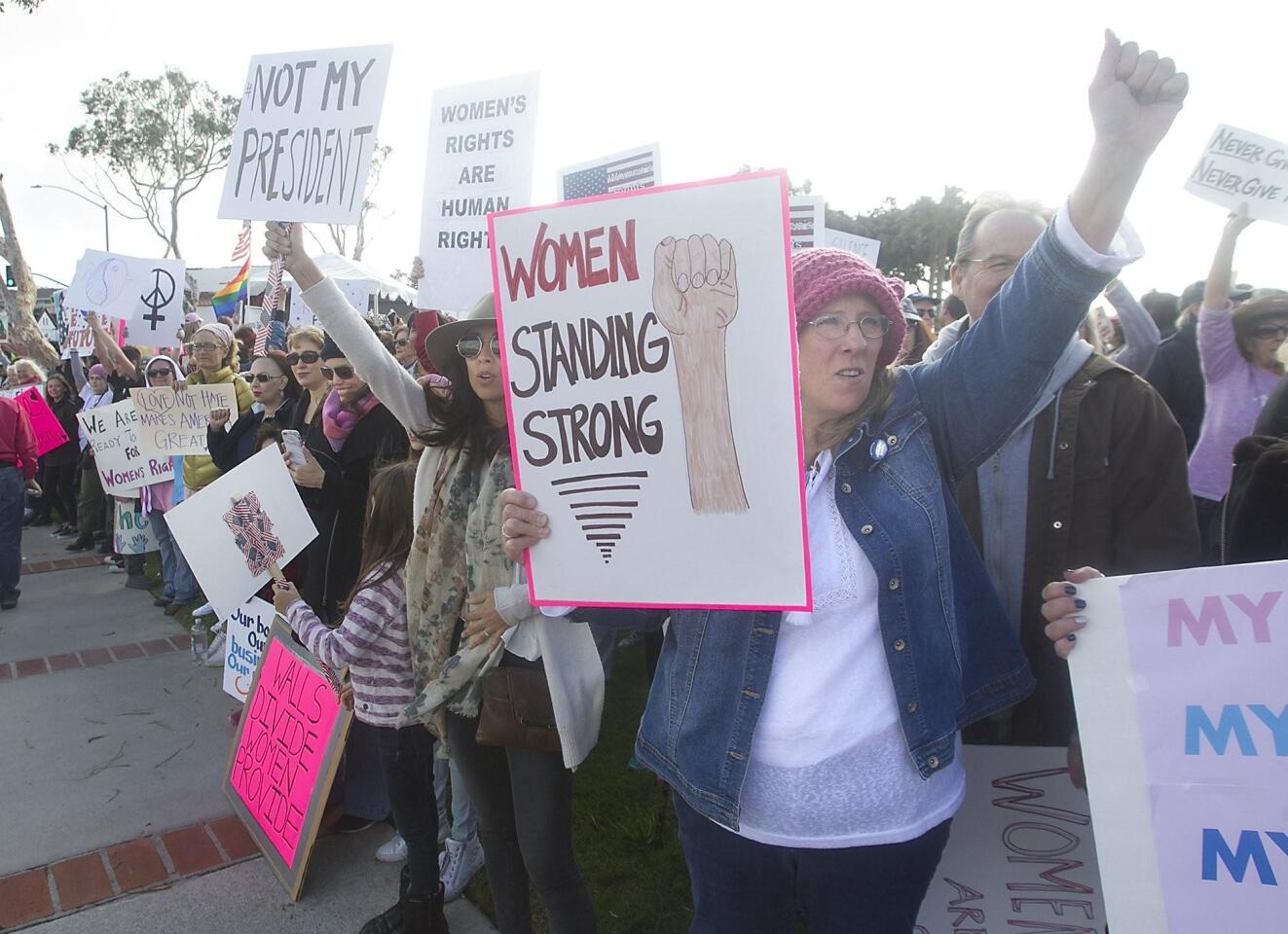 Hundreds of demonstrators hold signs as they participate in the Laguna Beach Women’s March at Main Beach in Laguna Beach on Saturday.