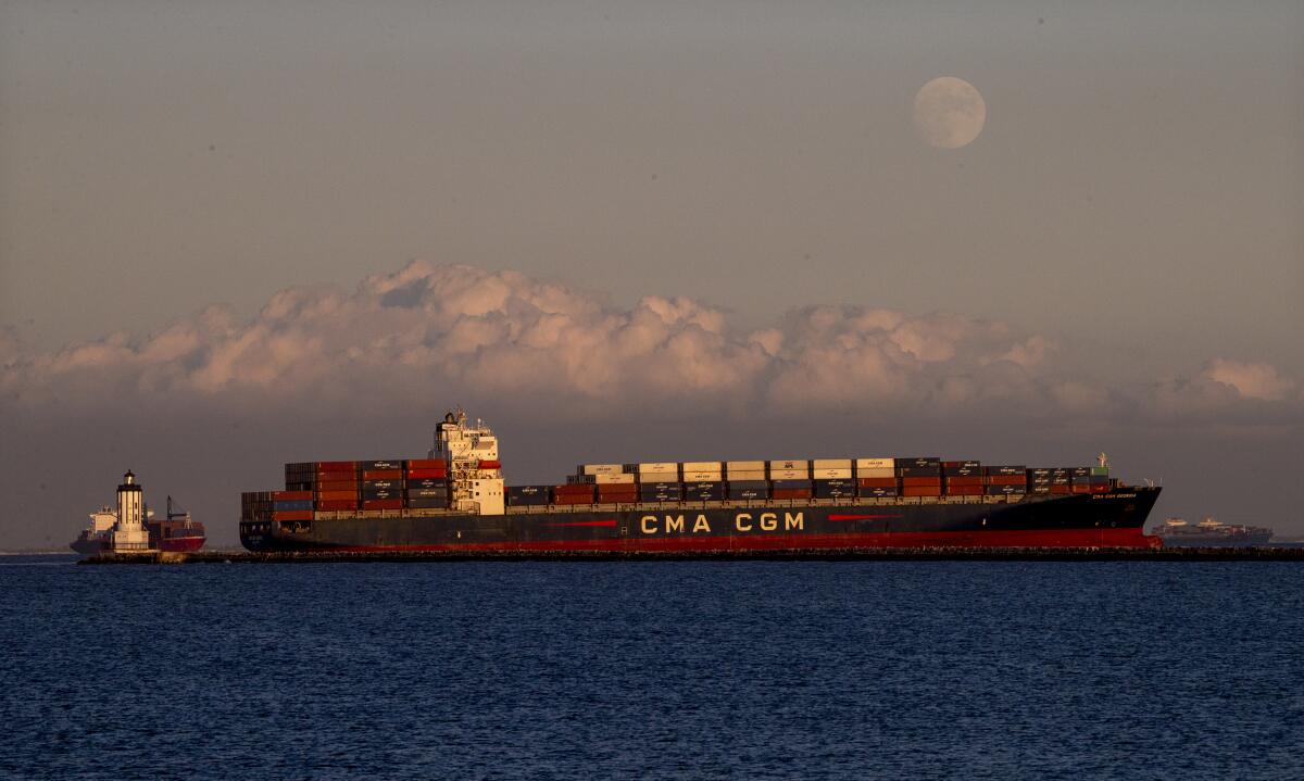 The moon rises over a cargo ship off the coast of Long Beach