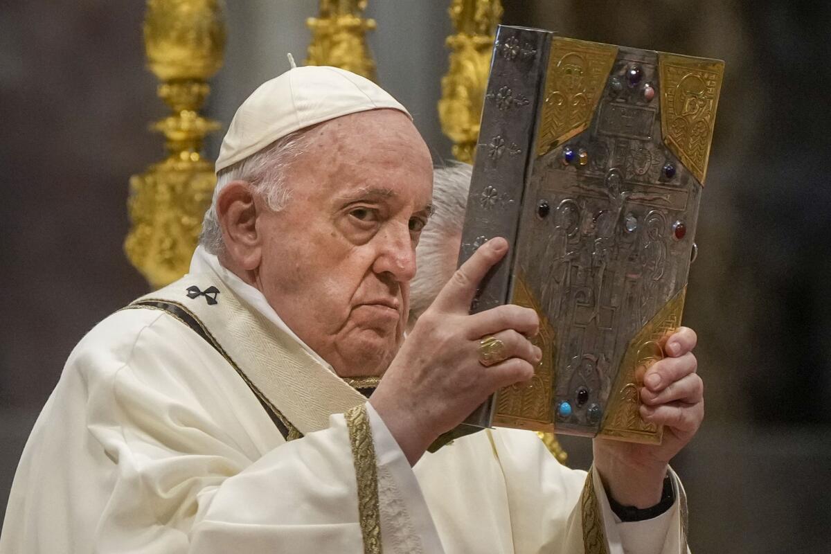 Pope Francis hoists the Gospel book during a Chrism Mass inside St. Peter's Basilica, at the Vatican on Thursday.
