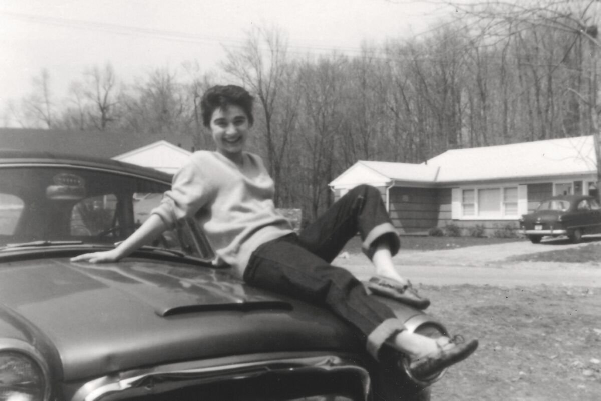 Kitty Genovese sits on the hood of a '50s-era car.