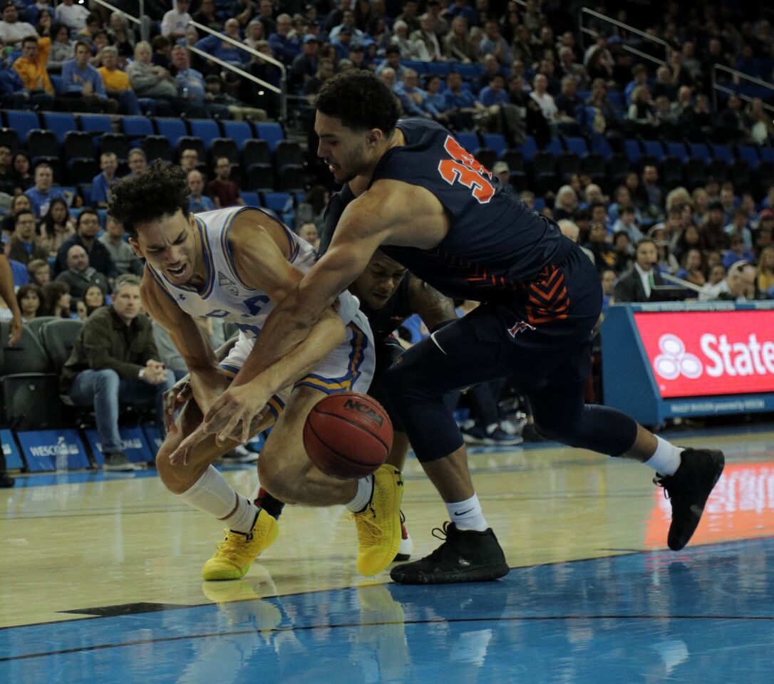 UCLA guard Jules Bernard and Fullerton forward Jackson Rowe battle for a loose ball in the second half.