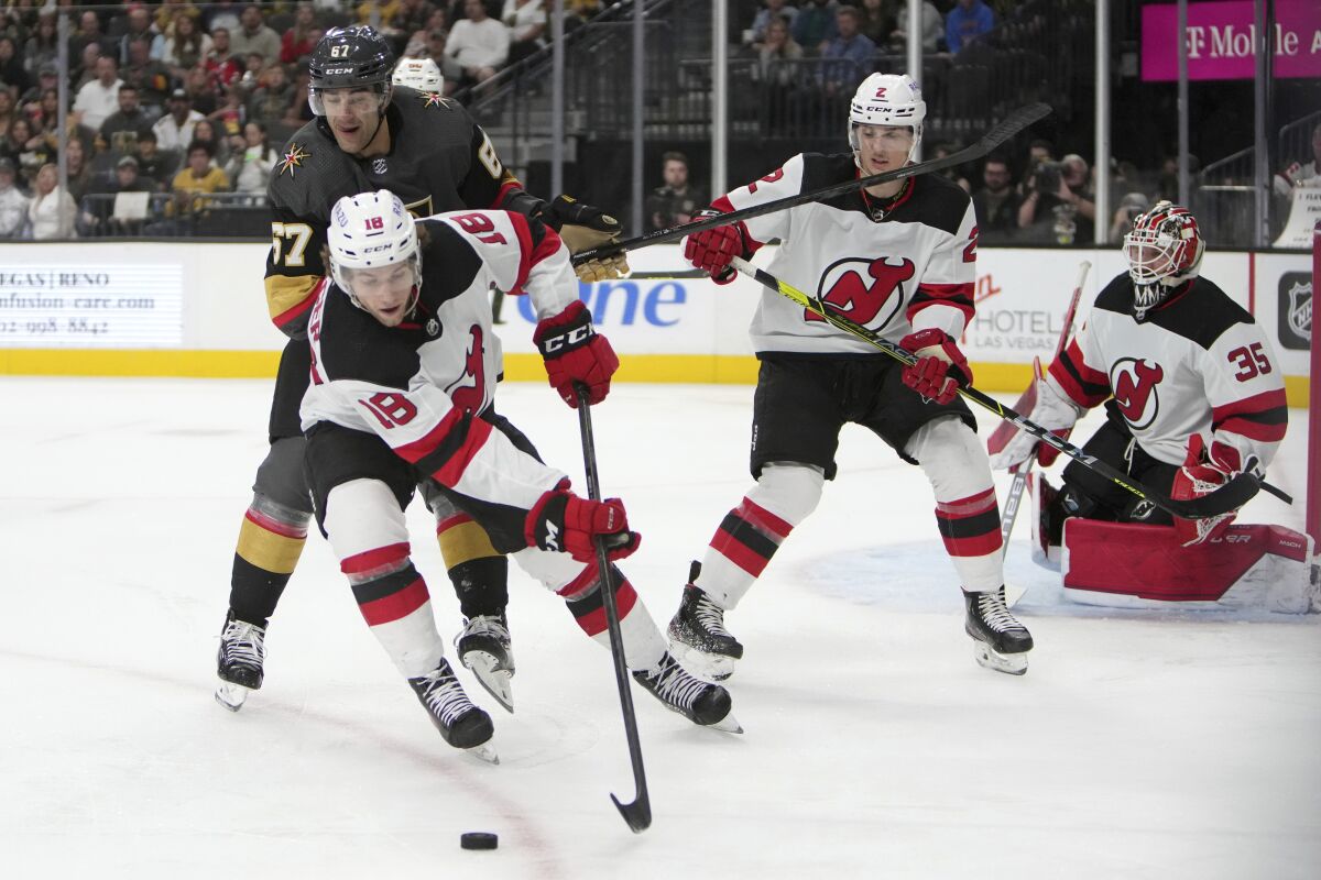 New Jersey Devils center Dawson Mercer (18) gathers the puck against Vegas Golden Knights left wing Max Pacioretty (67) during the second period of an NHL hockey game Monday, April 18, 2022, in Las Vegas. (AP Photo/Joe Buglewicz)