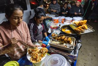 Los Angeles, CA - December 20: Yesenia Tunay, 16, left, her mom, Tina Tunay, and dad, Diego Tunay serve and cook a variety of dishes on a makeshift grill set up on the sidewalk at the Guatemalan Night Market - two streets in Westlake that sell authentic Guatemalan food and have become a gathering spot for Guatemalans in Los Angeles Wednesday, Dec. 20, 2023. (Allen J. Schaben / Los Angeles Times)