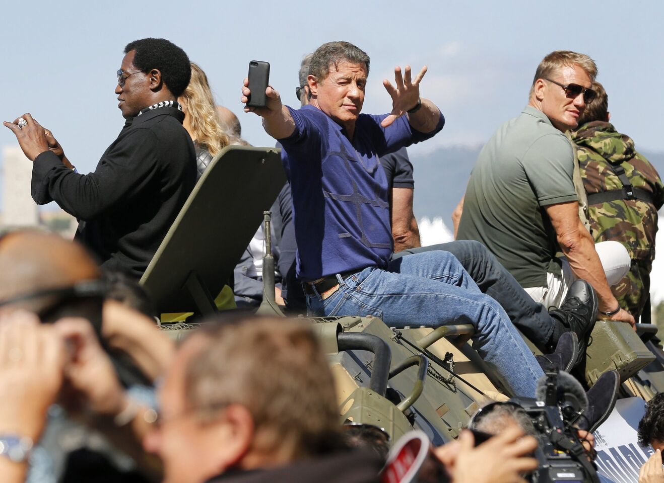 Sylvester Stallone, center, takes a selfie as he arrives on a tank for a photocall for "The Expendables 3" at the 67th annual Cannes Film Festival in Cannes, France, on May 18, 2014.
