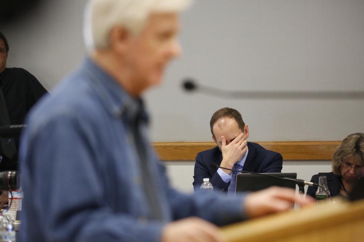 Charles Lester reacts to speakers during a long commission hearing on a vote for his dismissal.