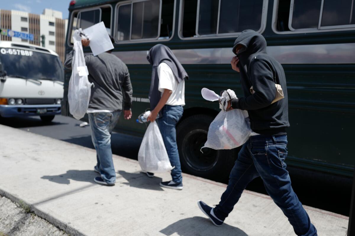 Los guatemaltecos deportados de EE.UU se dirigen hacia los autobuses provistos por el gobierno para llevarlos a casa.