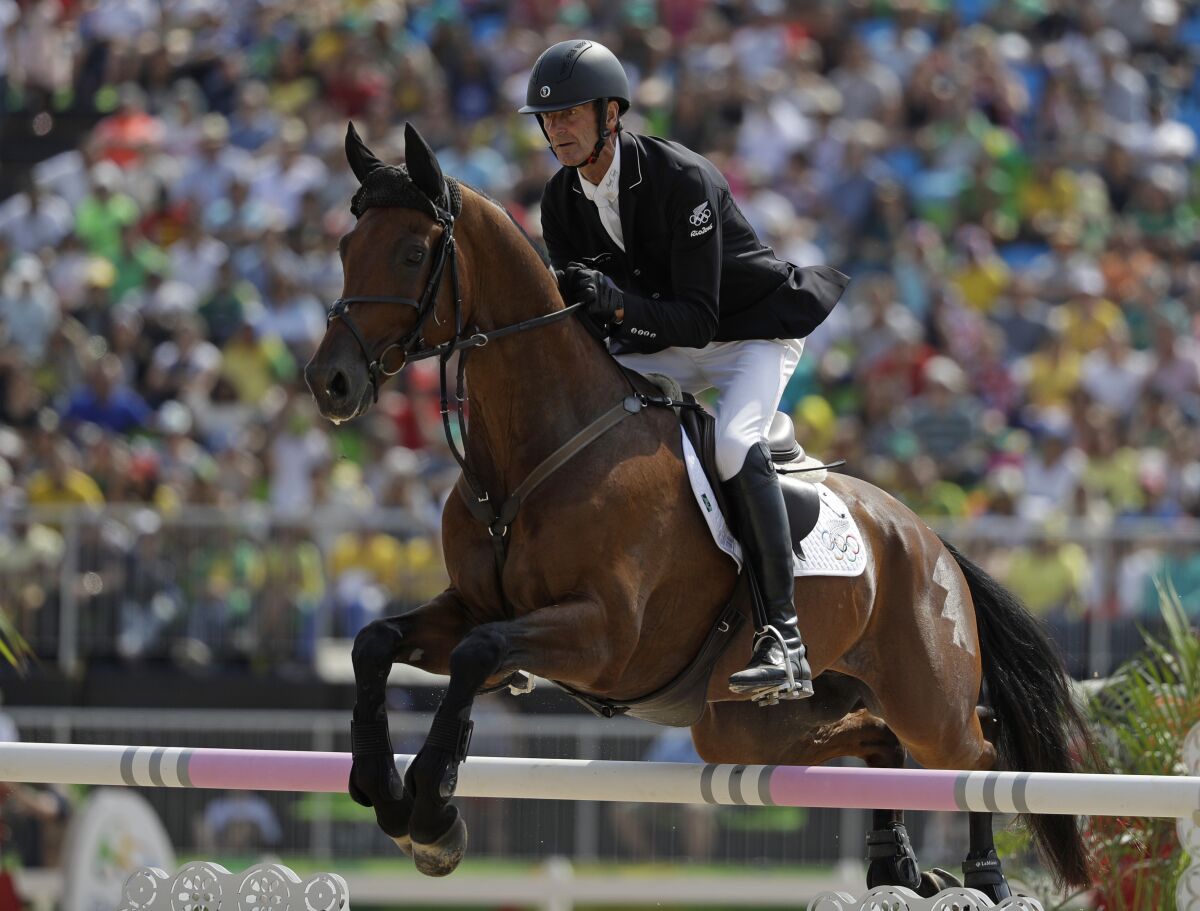 FILE - Mark Todd, of New Zealand, riding Leonidas II, competes in the equestrian eventing team show jumping phase at the 2016 Summer Olympics in Rio de Janeiro, Brazil, on Aug. 9, 2016. Two-time Olympic equestrian champion Mark Todd has temporarily lost his license as a racehorse trainer pending an investigation into a video showing him striking a horse with a branch. The British Horseracing Authority has imposed the interim suspension on the 65-year-old New Zealander preventing him from racing horses in Britain or internationally. (AP Photo/John Locher, File)