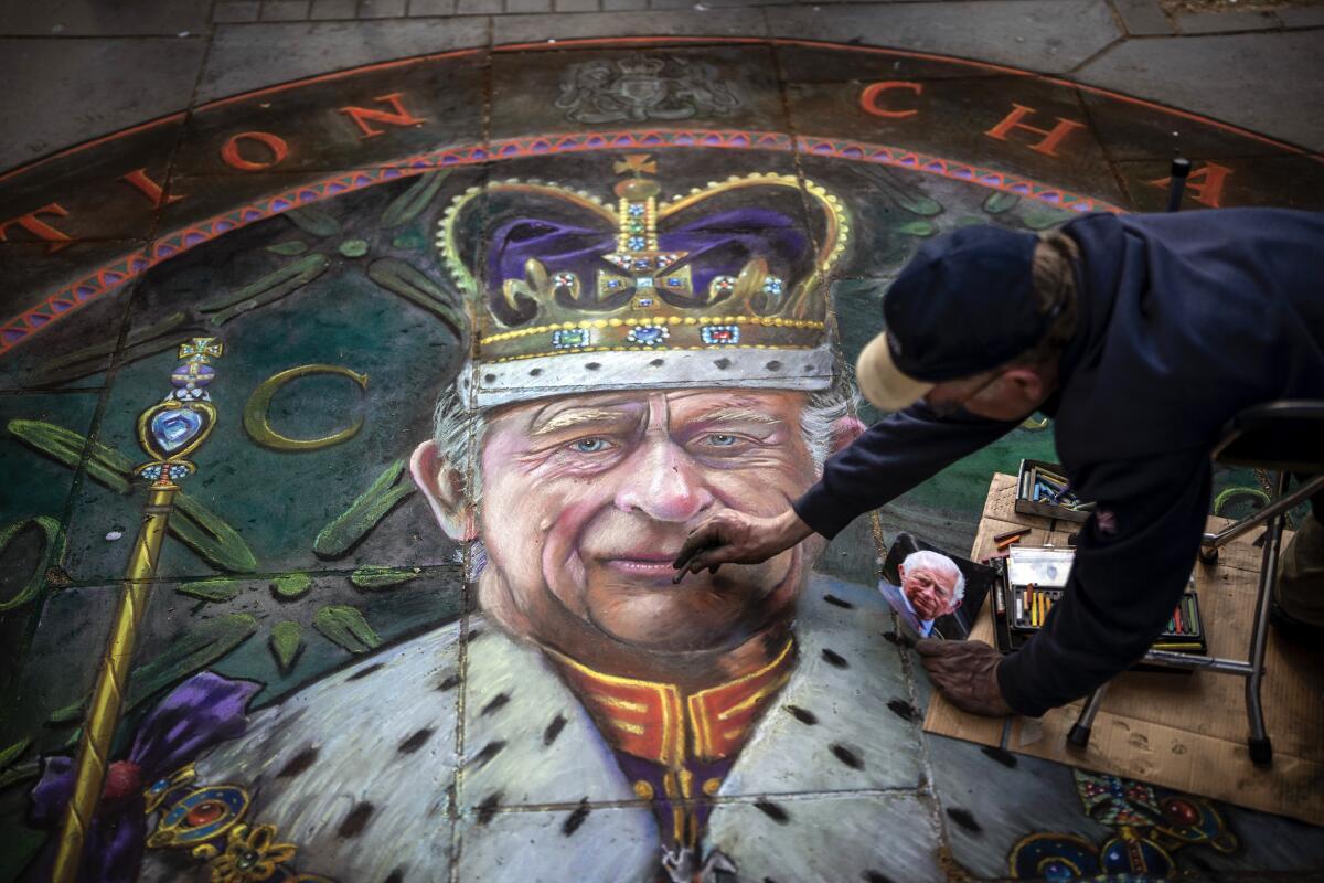 British artist Julian Beaver works on a round image of King Charles III in robes on the ground on Thursday.