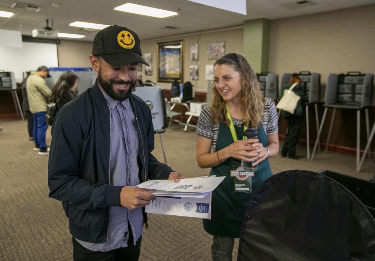 Christina Krebs, right, assists Brandon Mendez in processing his ballot at the Huntington Beach City Hall on Tuesday.