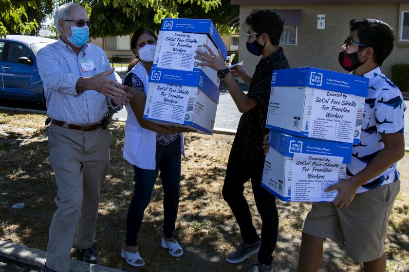 HEMET, CA - AUGUST 7, 2020: Zubin Carvalho, 14, left and his brother Tenzing,12, give boxes of their homemade face shields to Meadowbrook Health Care Center Administrator Mike Elbert and Raji Sandhills, director of nursing, on August 7, 2020 in Hemet, California. The Carvalho's have made more than 12,500 face shields using a 3D printer which they have distributed to frontline workers at schools, hospitals and nursing homes.(Gina Ferazzi / Los Angeles Times)