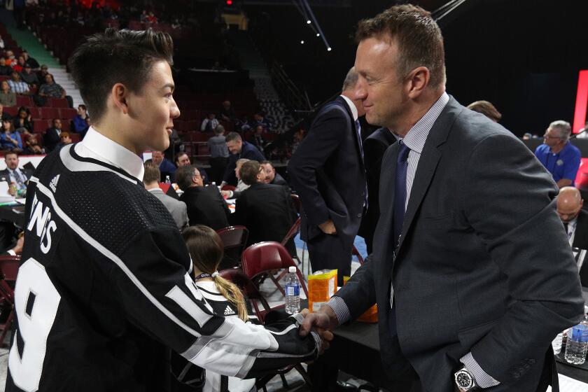 VANCOUVER, BRITISH COLUMBIA - JUNE 22: Jordan Spence, 95th overall pick of the Los Angeles Kings, is greeted by Rob Blake at the team draft table during Rounds 2-7 of the 2019 NHL Draft at Rogers Arena on June 22, 2019 in Vancouver, Canada. (Photo by Dave Sandford/NHLI via Getty Images)