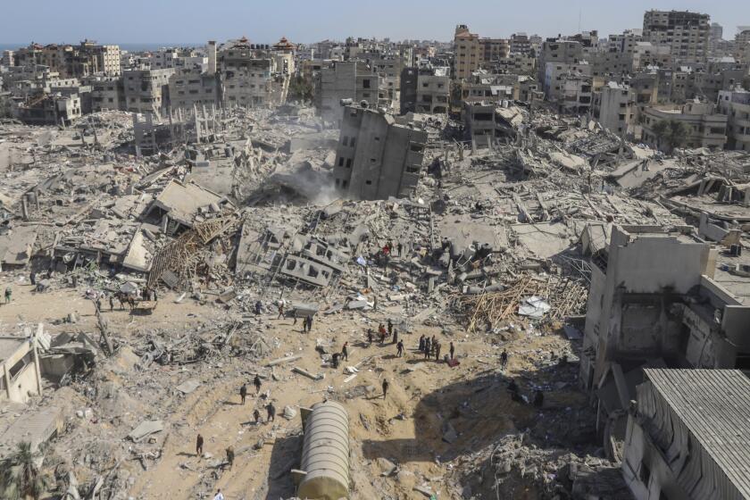 Palestinos caminan entre una zona devastada por la ofensiva aérea y terrestre de Israel cerca del hospital Shifa, el lunes 1 de abril de 2024, en Ciudad de Gaza, Franja de Gaza. (AP Foto/Mohammed Hajjar)