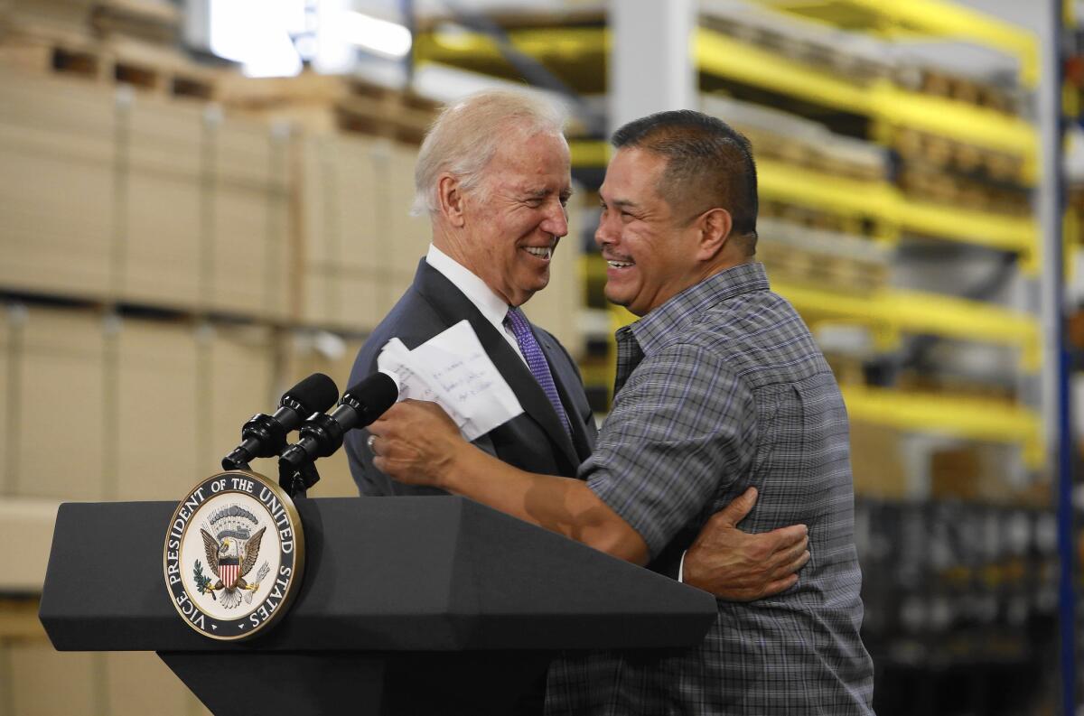 Joe Biden embraces a man behind a lectern with the vice presidential seal