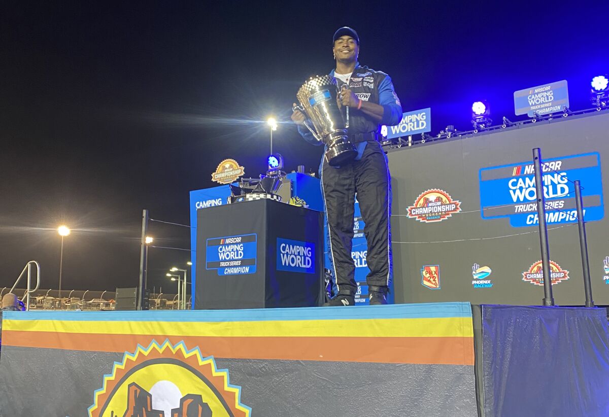 Tyriq McCord stands on the winner's podium with the NASCAR truck series championship trophy at Phoenix Raceway.