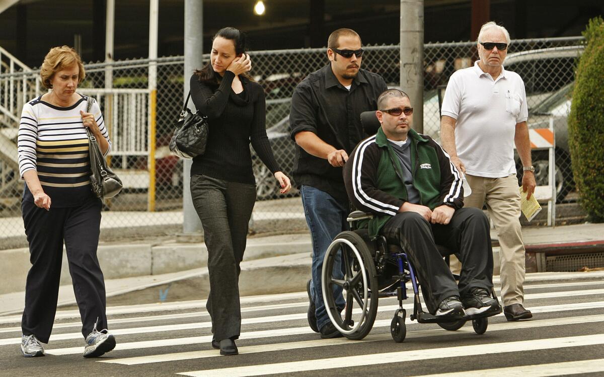 Bryan Stow, in a wheelchair, is pushed by a caregiver as he and, from left, his mother, Ann Stow, sister Bonnie Stow and father, David Stow, head into the Los Angeles County Superior Courthouse in downtown L.A. in June 2014.