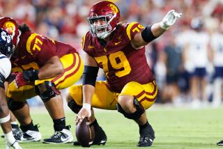 UCLA center Jonah Monheim points and shouts while kneeling over the ball during a game against Utah State