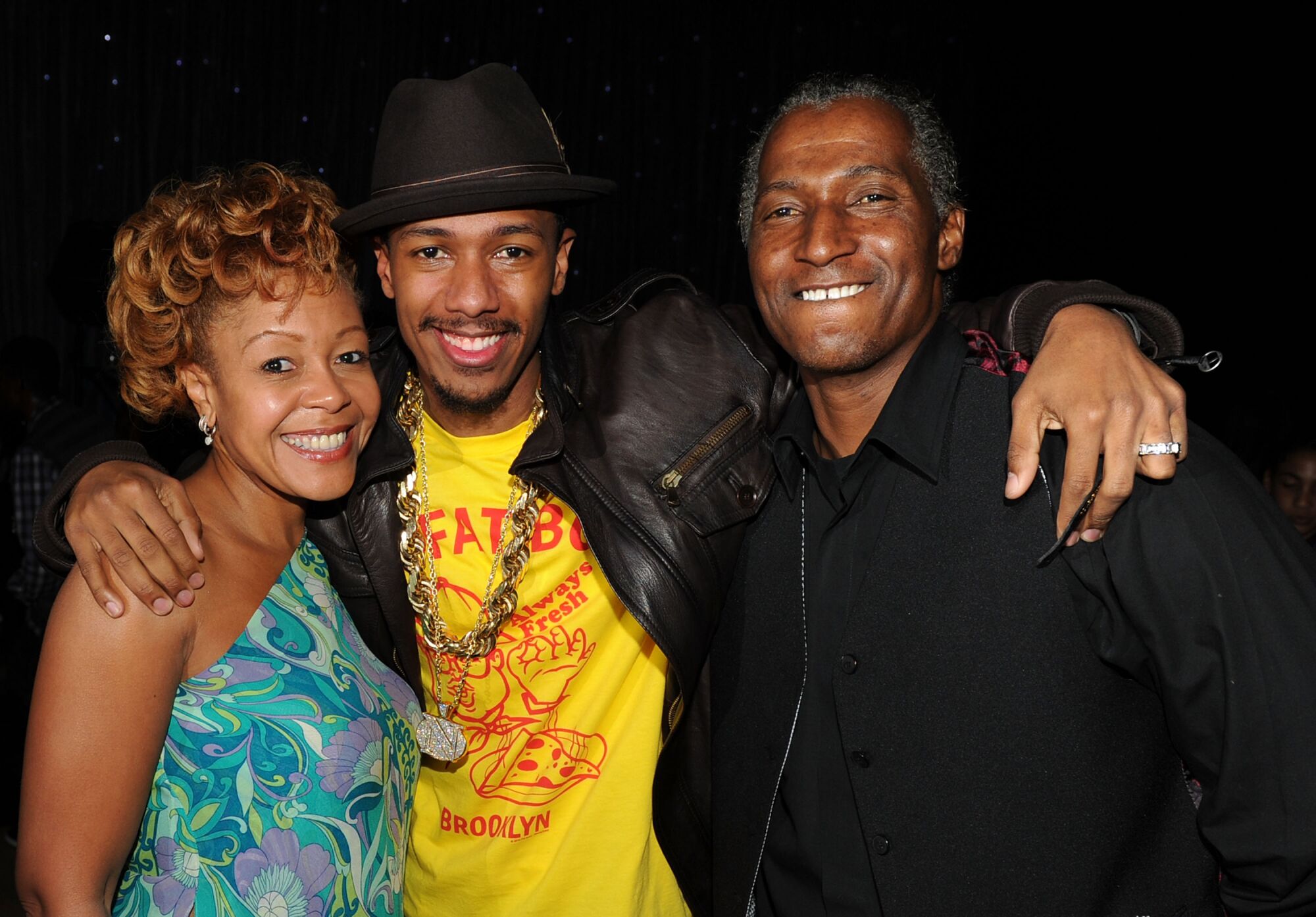 A man in a hat stands with his arms around his mom and dad