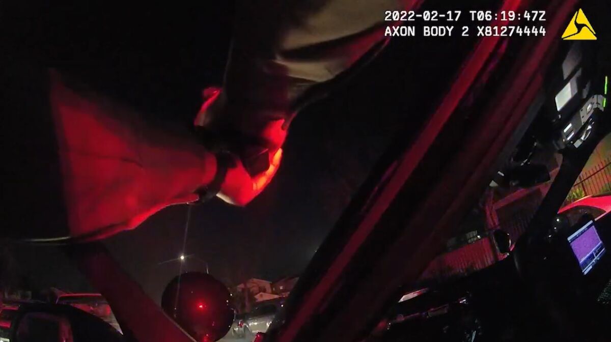Image from Deputy David Lovejoy's body-worn camera shows his arm extended across his open cruiser door at night.