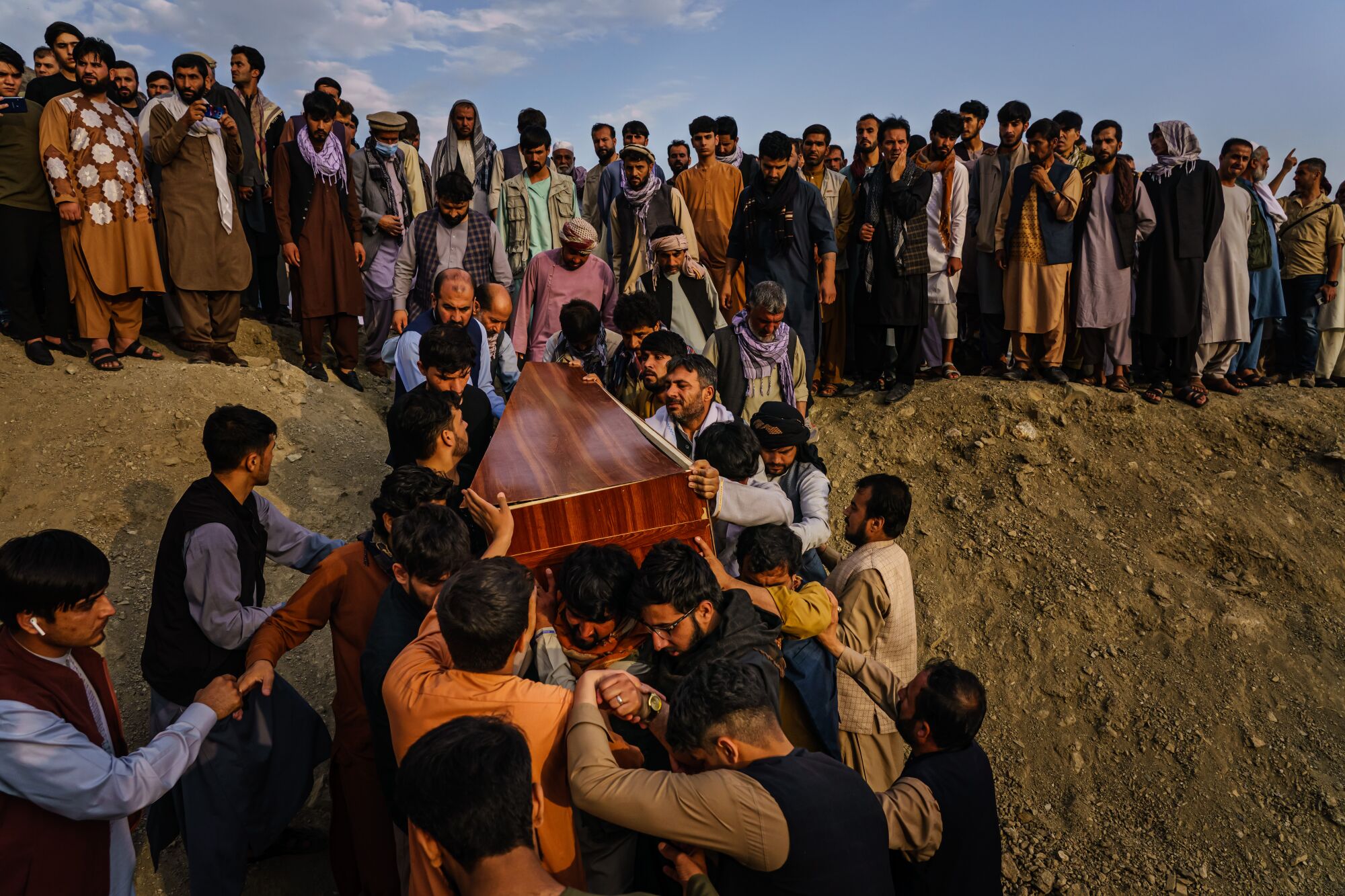 Caskets for the dead are carried toward the gravesite as relatives and friends attend a mass funeral for members of a family.