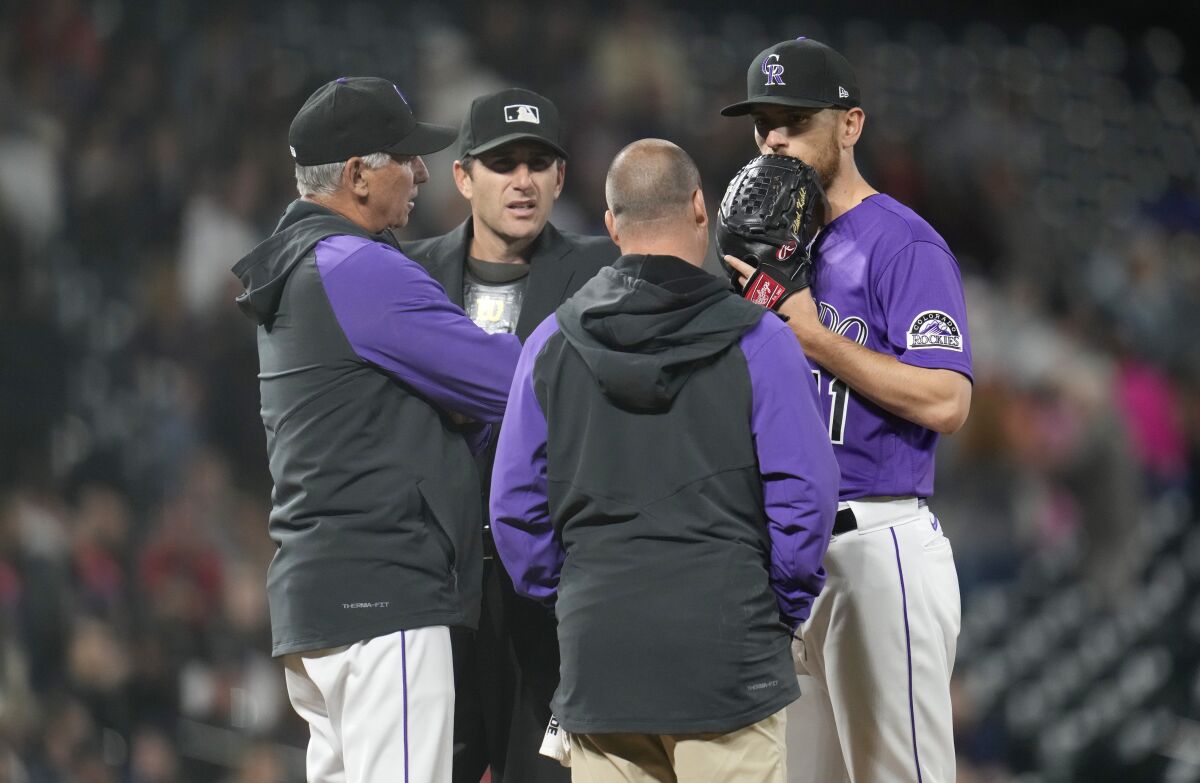 Colorado Rockies starting pitcher Chad Kuhl, right, confers with trainer Heath Townsend, second from right, home plate umpire Pat Hoberg, second from left, and manager Bud Black, left, as Kuhl is pulled from the mound before facing a Philadelphia Phillies batter in the seventh inning of a baseball game Monday, April 18, 2022, in Denver. (AP Photo/David Zalubowski)