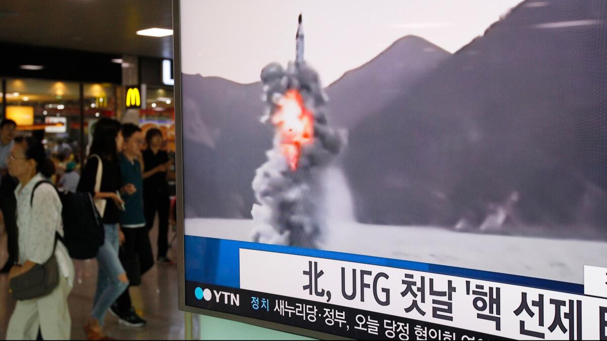People in Seoul pass by a TV news program showing file footage of North Korea's ballistic missile that the North claimed to have launched from underwater on Aug. 24, 2016.
