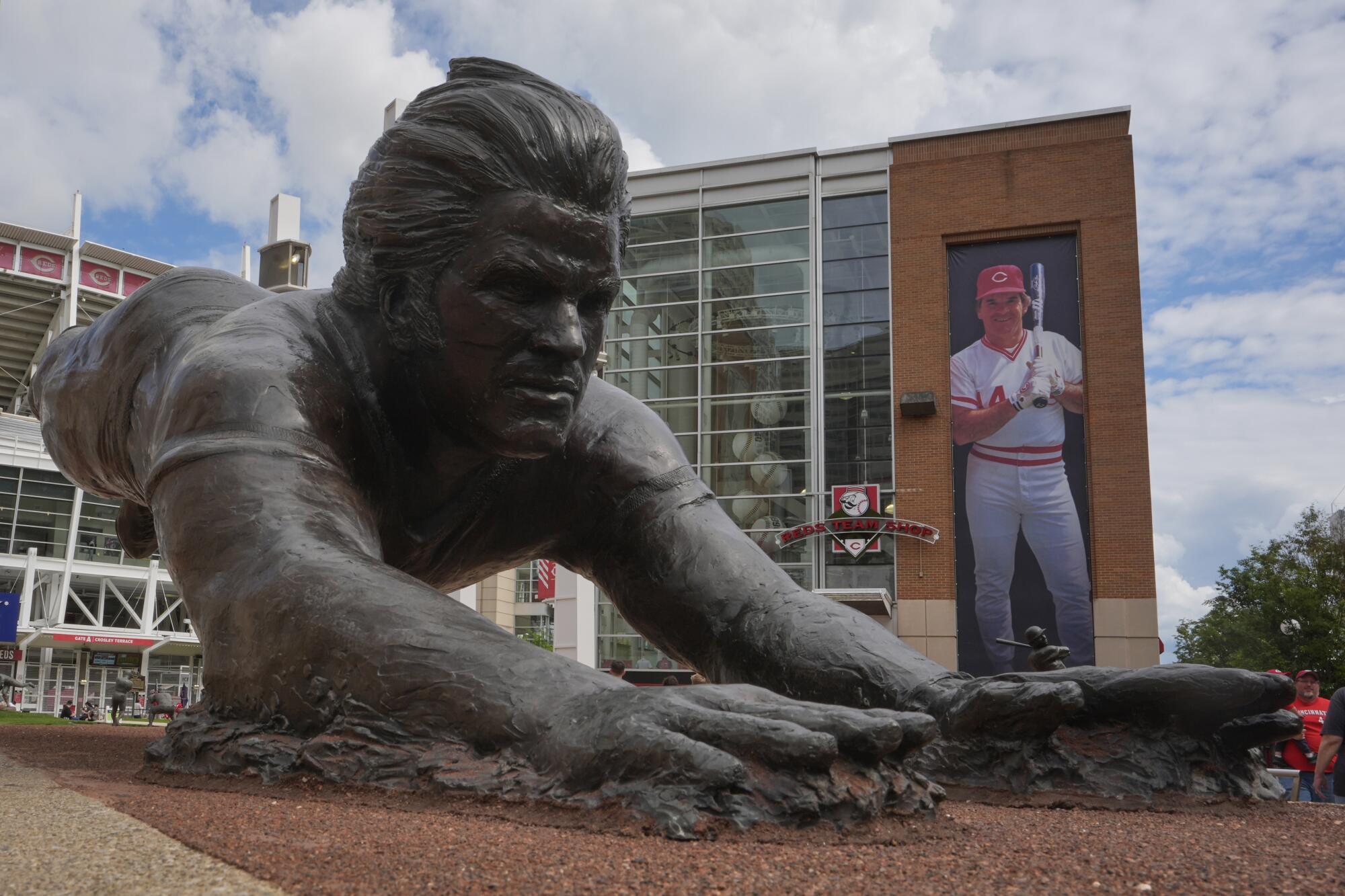 A bronze statue and banner of former Cincinnati Reds player Pete Rose are seen outside Great American Ball Park, Tuesday