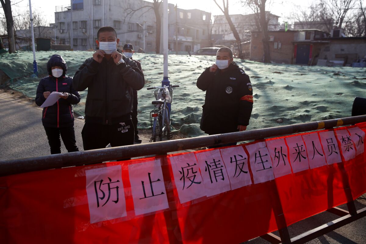Chinese public security volunteers stand at an entrance their community in Beijing to register personal information of people returning from outside the city.