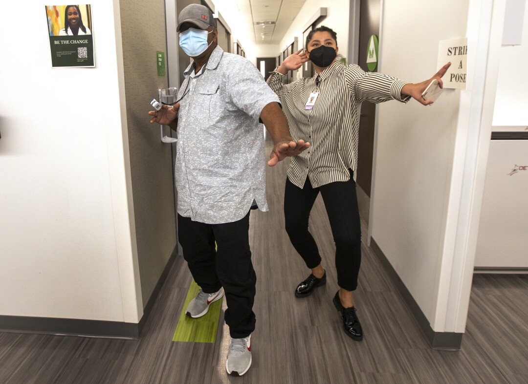 Richard Perry and a medical worker, both standing, strike a playful pose for the camera.
