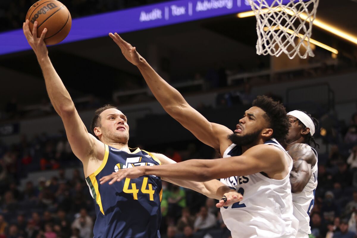 Utah Jazz forward Bojan Bogdanovic (44) shoots the ball over Minnesota Timberwolves center Karl-Anthony Towns (32) during the first half of an NBA basketball game Wednesday Dec. 8, 2021, in Minneapolis. (AP Photo/Stacy Bengs)