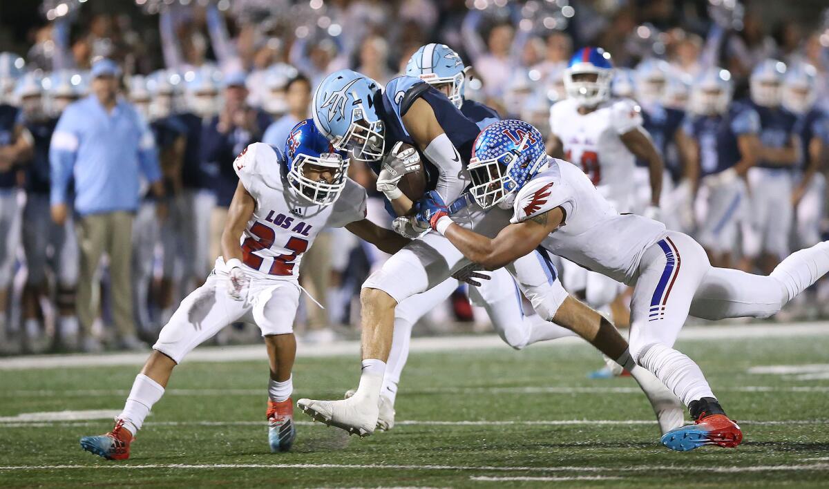 Corona del Mar’s Tommy Griffin returns an interception and is brought down by Los Alamitos’ Gavin Porch, left, and Giovanni De Leon in a Sunset League game at Davidson Field on Nov. 9, 2019.