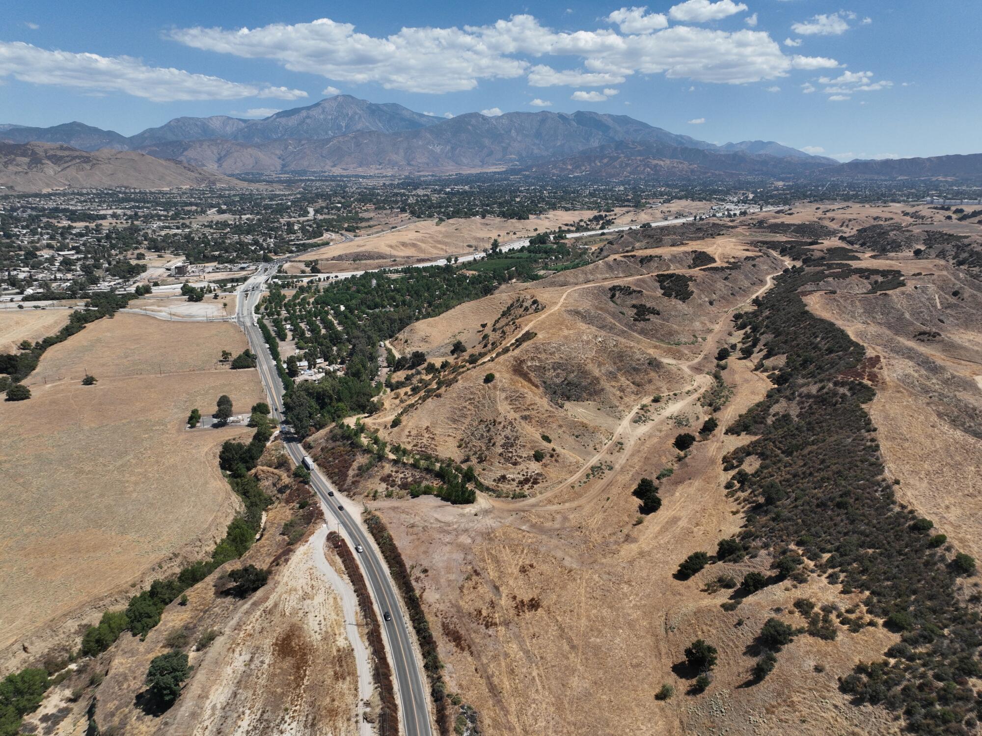 An aerial view of a freeway cutting trough large hills. 