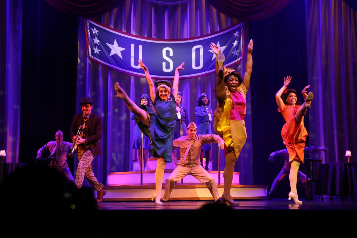 Dancers perform onstage in front of a banner that says USO in "Rogers: The Musical" at Disney California Adventure.