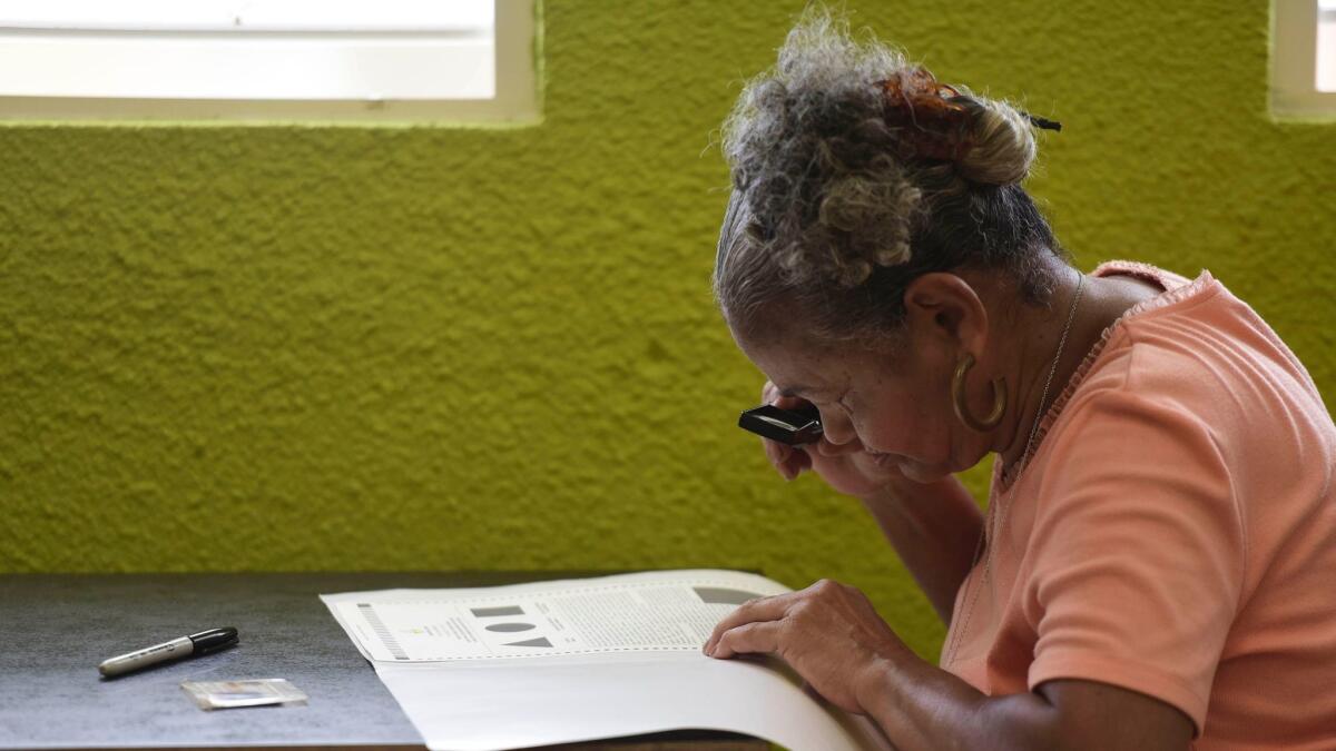 Marla Quinones examines her ballot with a magnifying glass before voting in Puerto Rico's fifth referendum on statehood in San Juan.