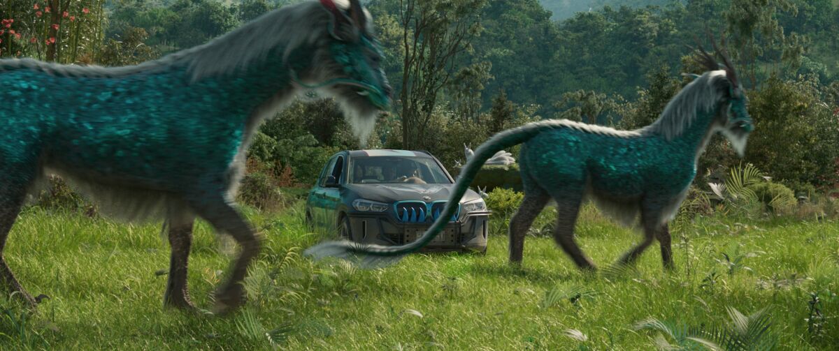a car in a field surrounded by horse-like creatures with shiny scales