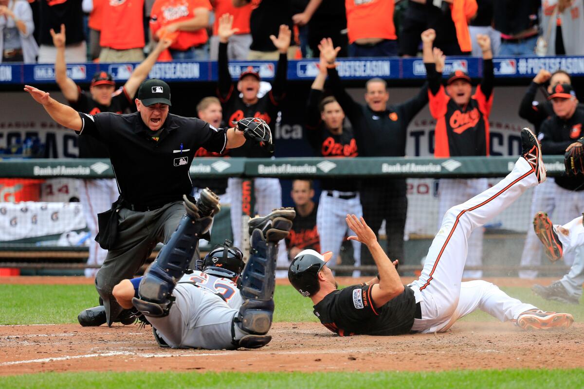 Baltimore's J.J. Hardy, right, is one of three runners to score off an eighth-inning double by Delmon Young as the Orioles rally to take Game 2 of their ALDS game against Detroit.