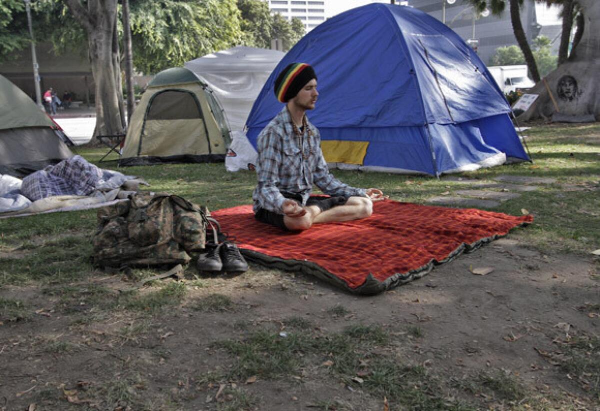 Amid the ongoing Occupy encampment of the City Hall lawn, Jacob English pauses to meditate. Veteran meditators appear better able to rein in their wandering thoughts.