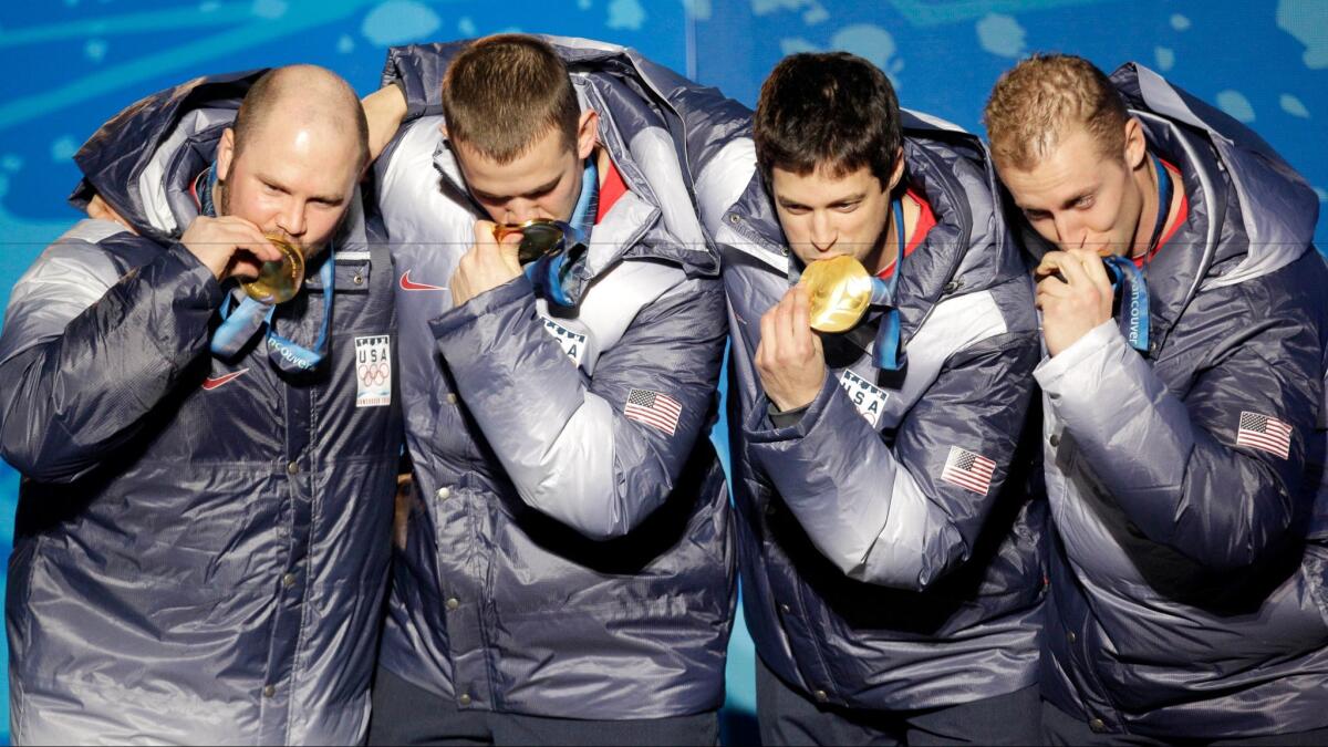 In this Feb. 27, 2010, file photo, from left, Steven Holcomb, Justin Olsen, Steve Mesler and Curtis Tomasevicz, of the United States, kiss their gold medals during the medal ceremony of the 2010 Olympics in Whistler, British Columbia.