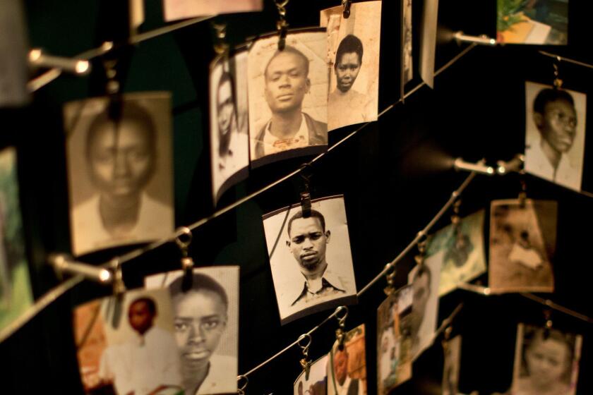 FILE - In this Saturday, April 5, 2014 file photo, family photographs of some of those who died hang in a display in the Kigali Genocide Memorial Centre in Kigali, Rwanda. Mass graves in Rwanda that authorities say could contain more than 2,000 bodies have been discovered in April 2018, nearly a quarter-century after the country's genocide. (AP Photo/Ben Curtis, File)