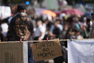 A protest sign saying Turist go home is displayed on a makeshift clothesline during a demonstration against gentrification.