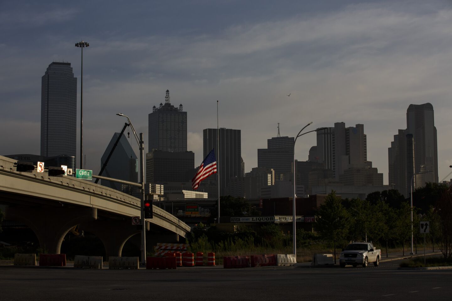 A large American flag flies at half mast framed by the Dallas skyline in the aftermath of the deadly police shooting.