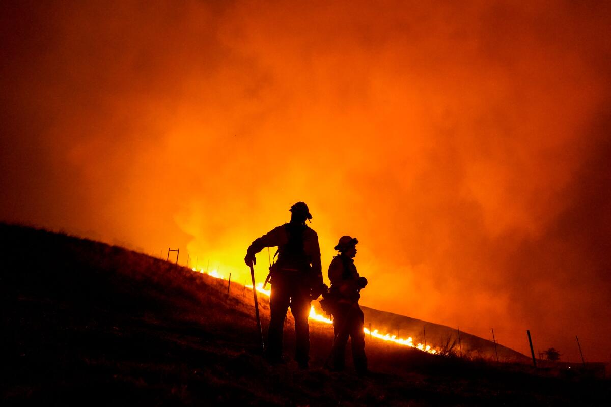 Santa Rosa Fire Department Firefighters stand, watching the Shady Fire as it makes its way towards homes on Sept. 27, 2020.