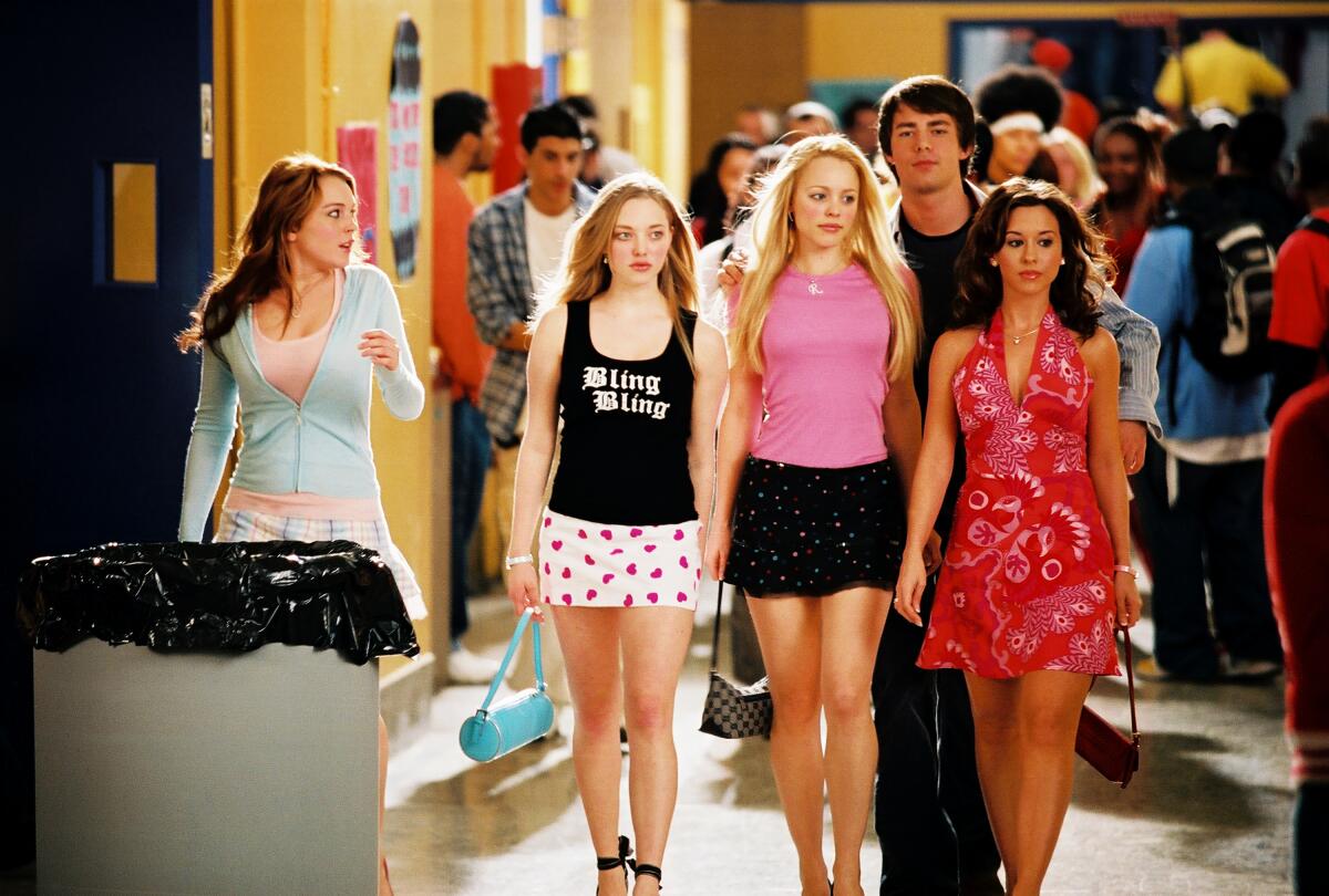 Amanda Seyfried, Rachel McAdams, Lacey Chabert walk in a tight row down a school hallway next to Lindsay Lohan