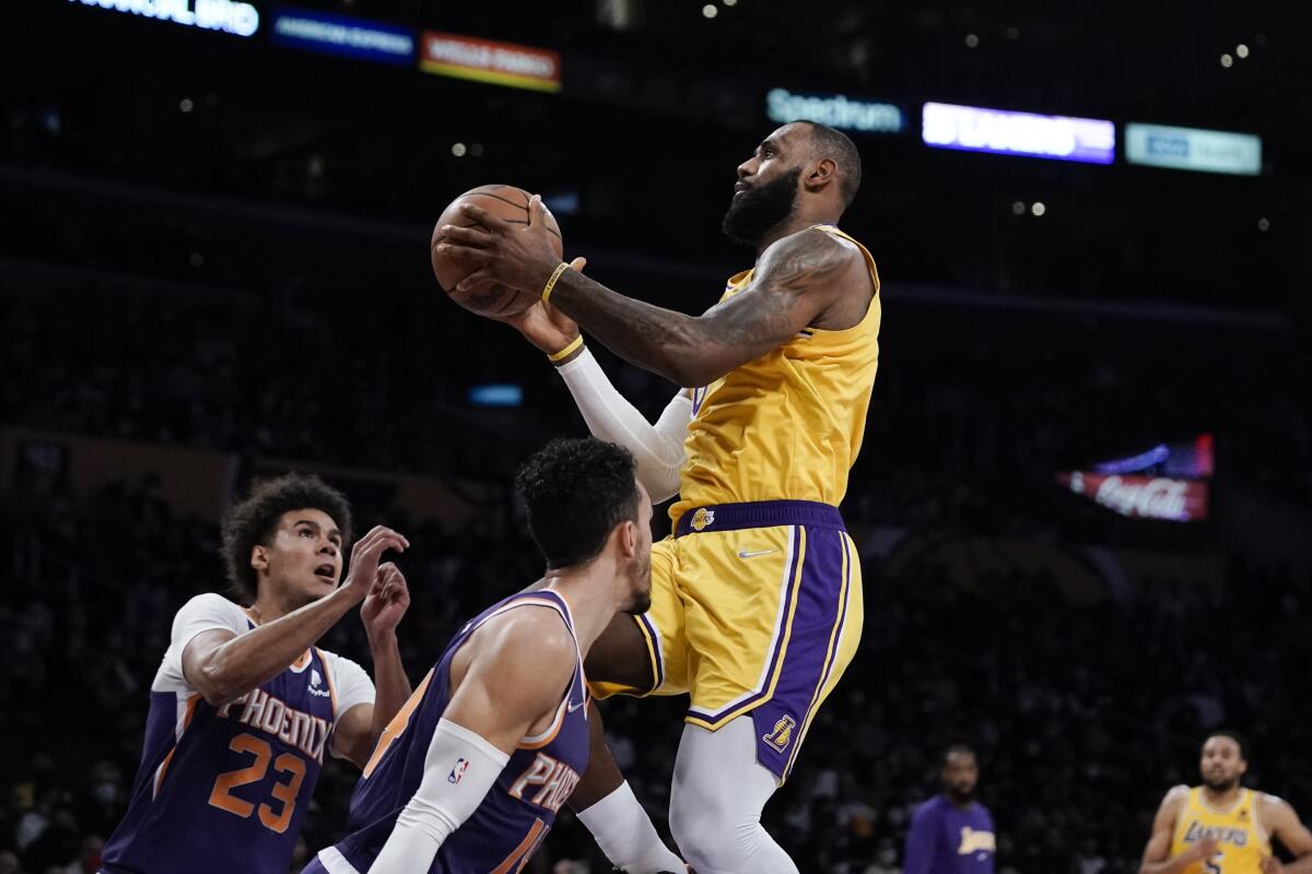 Lakers star LeBron James goes up for a shot as Phoenix's Cameron Johnson and Landry Shamet look on.