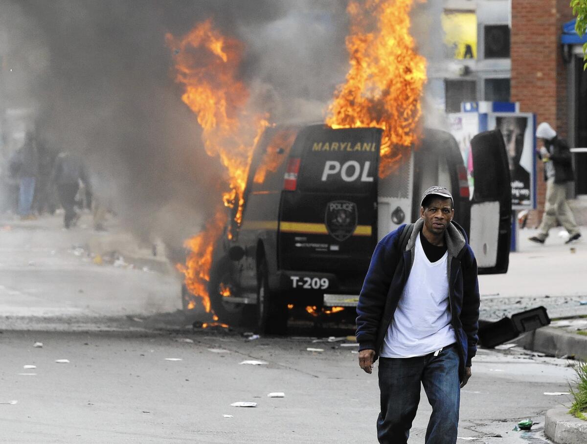A man walks past a burning police vehicle during unrest following the funeral on April 27 of Freddie Gray in Baltimore.
