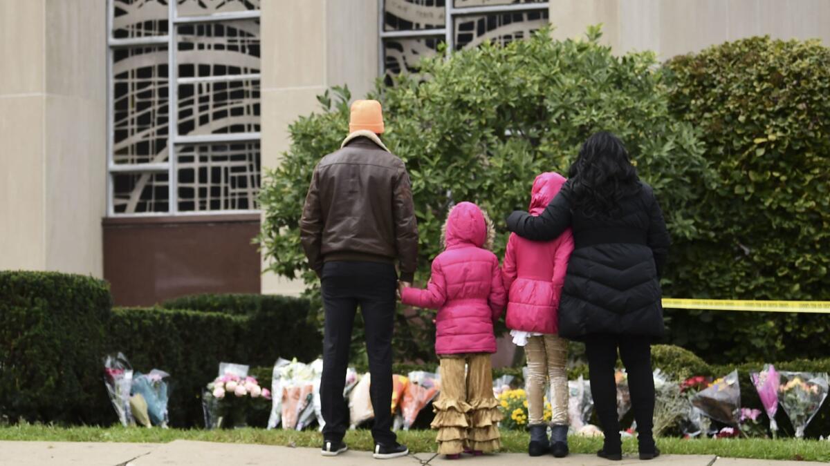 People stand in front of a memorial on Sunday outside of the Tree of Life Synagogue after a shooting there the day before left 11 people dead in the Squirrel Hill neighborhood of Pittsburgh.