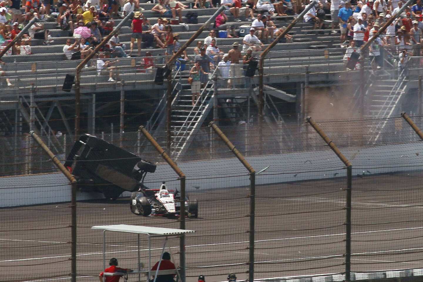 The car of driver Mike Conway slides along the retaining wall and fence after going airborne following a collision with the car of Will Power on Sunday at the Indy 500.