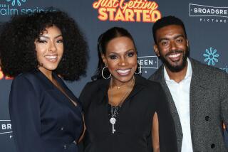 Sheryl Lee Ralph in black poses in between her children Ivy-Victoria Maurice in dark blue and Etienne Maurice in gray