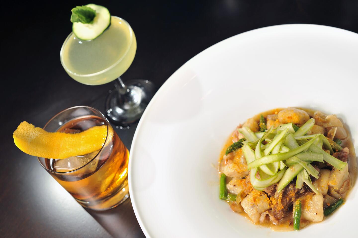 A plate of the roasted garlic gnocchi at Trattoria Neapolis with smoked pork shoulder, artichoke and asparagus, accompanied by an Easton, bottom, and the Doctor, top.